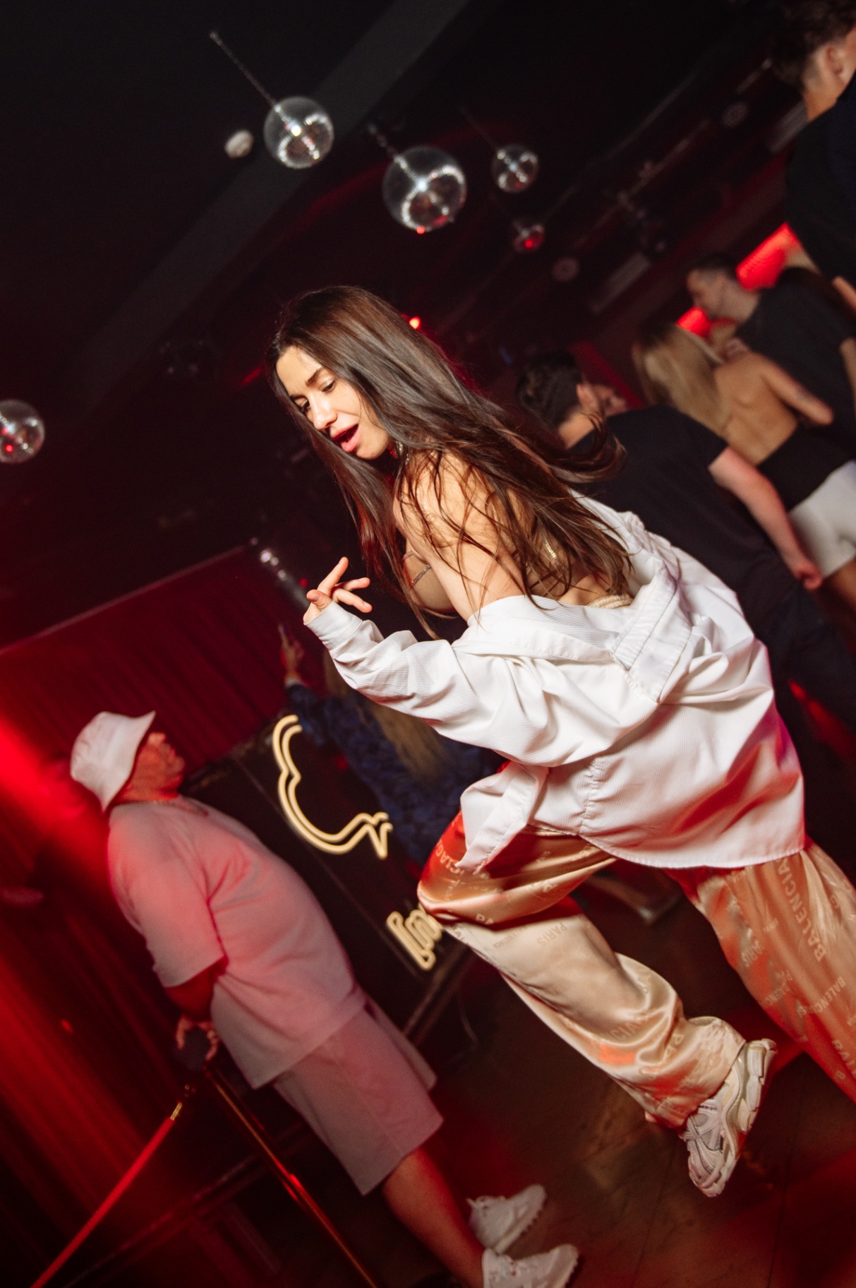 Dancer mid-move under disco balls in deep red light