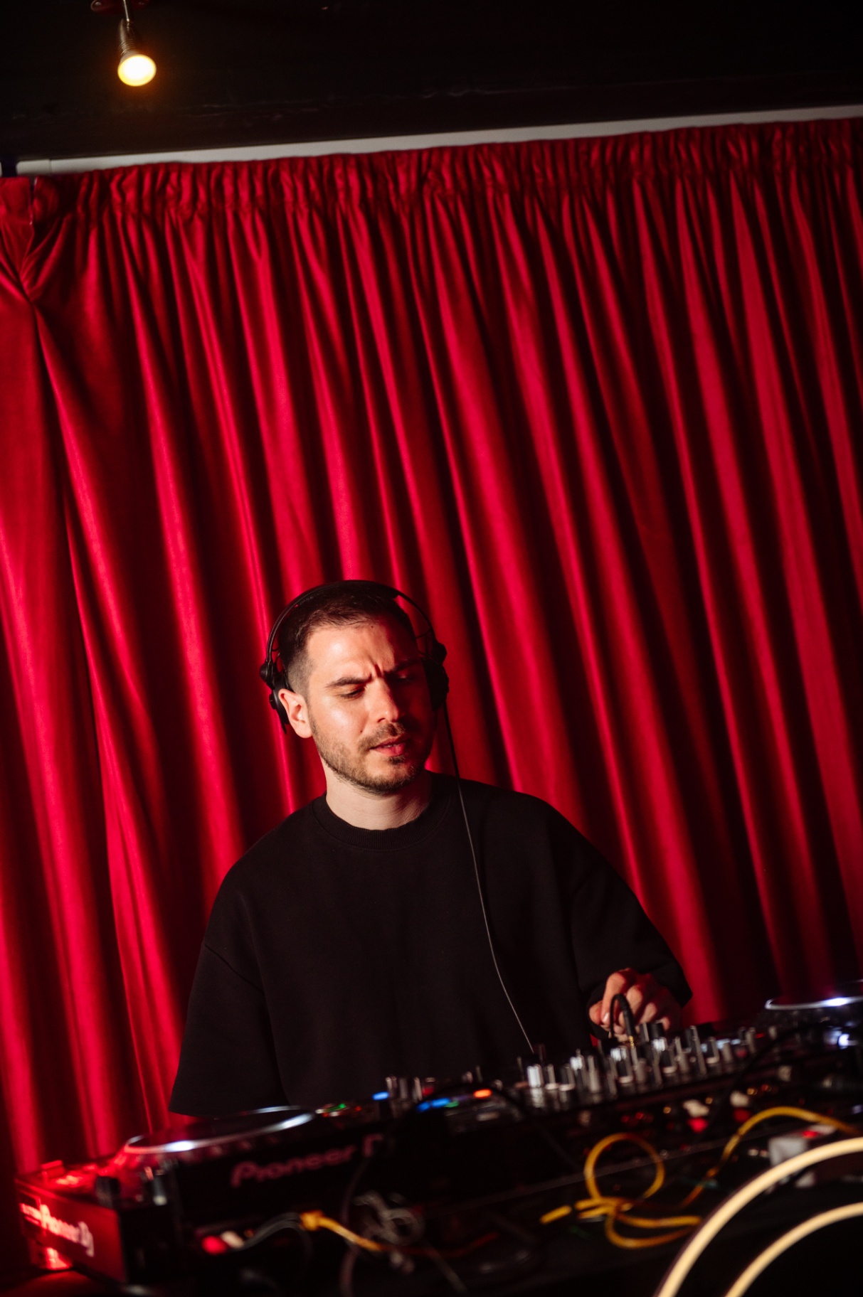 DJ playing in front of a deep red velvet curtain