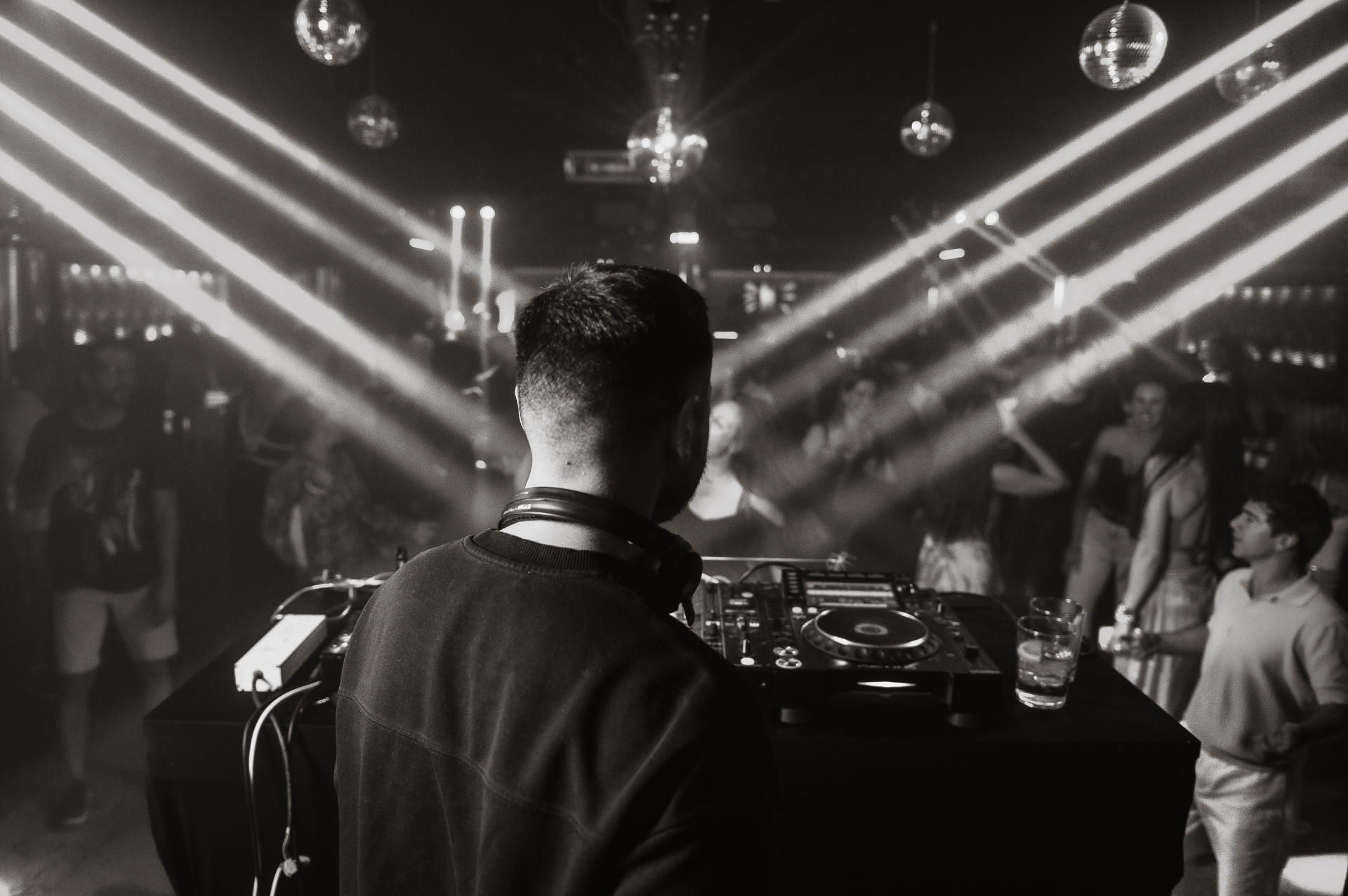 DJ behind the decks under laser beams and disco balls, black and white