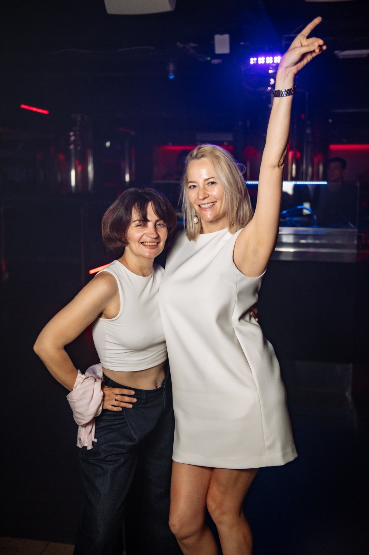 Two guests celebrating with a raised hand under the club lights