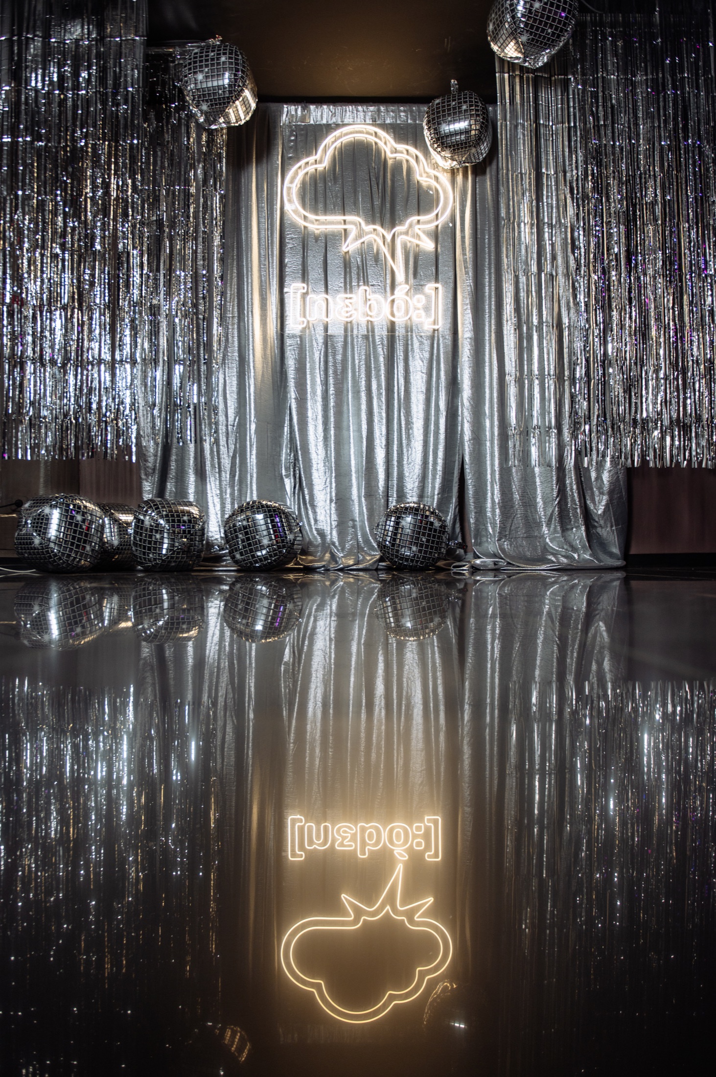 Mirrored [nɛbó:] installation surrounded by silver curtains and disco balls